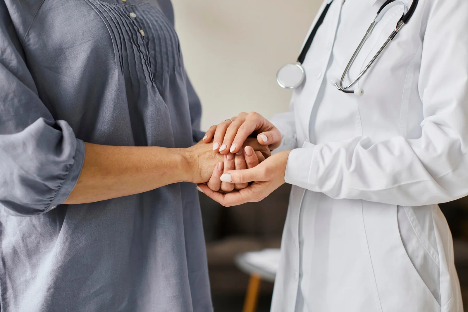 Una médica sostiene las manos de una paciente